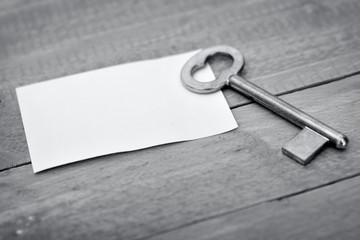 Key with empty note on wooden table