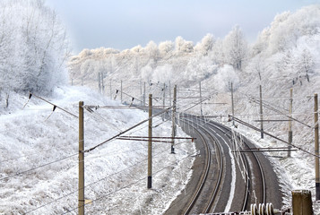 Empty electric mainline railroad in winter forest