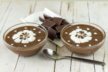 Шоколадный пудинг со взбитыми сливками на деревянном фоне.