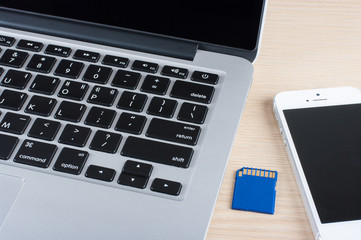 Laptop and smartphone on wood table background.