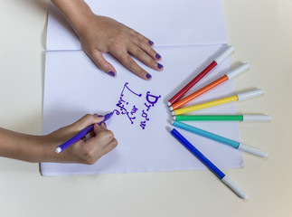 Ребенок рисует фломастерами на белой бумаге. Концепция образования, хобби, развлечение.