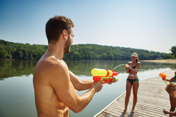 Familie spritzt mit Wasserpistolen und hat Spaß