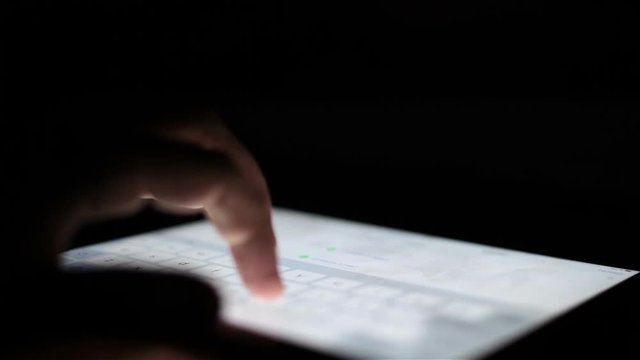 man touching tablet touch screen at dark