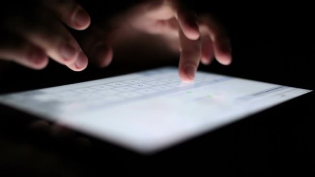 man touching tablet touch screen at dark