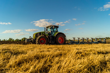 Naklejka premium Agriculture plowing tractor on wheat cereal fields
