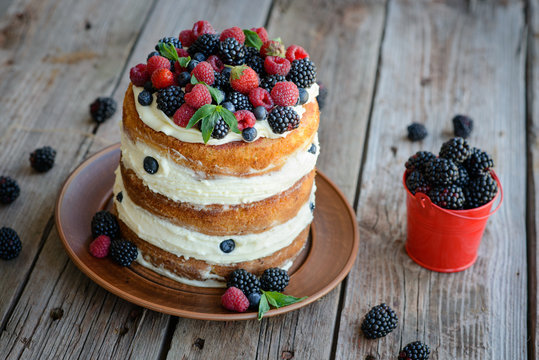 Tasty cake with strawberry, raspberry and blackberry on a wooden table