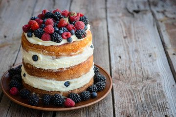 Tasty cake with strawberry, raspberry and blackberry on a wooden table