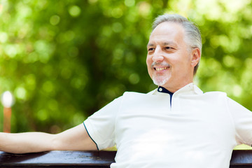 Elder man sitting at a bench in the park