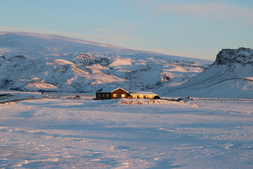 Типичный зимний пейзаж Исландии - одинокие дома посреди гор