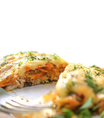Baked fish with cheese sauce, carrots and onions, decorated with fennel on a white background.