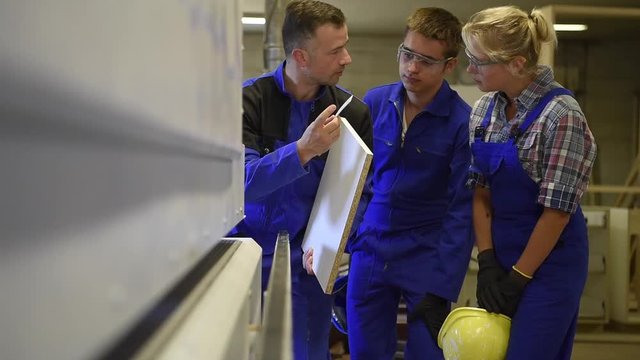 Professional teacher showing carpentry machinery to students