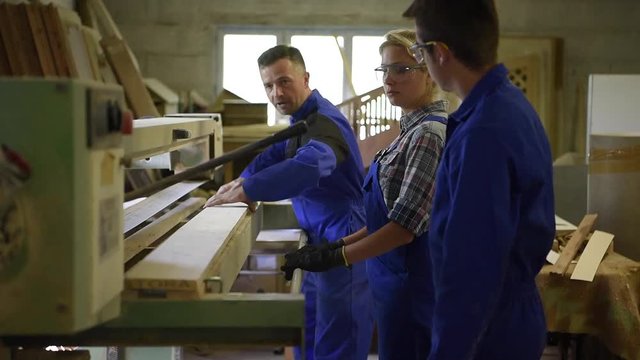 Professional teacher showing carpentry machinery to students