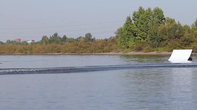 Rider wakeboard makes power rolling on the water. Beautiful splashes and waves. wakepark