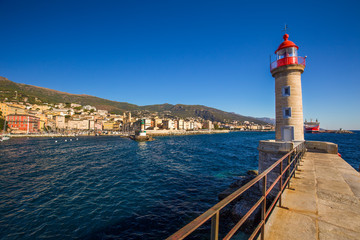 Fototapeta na wymiar Lighthouse in Bastia harbour with Joannis Babtistes Cathedral