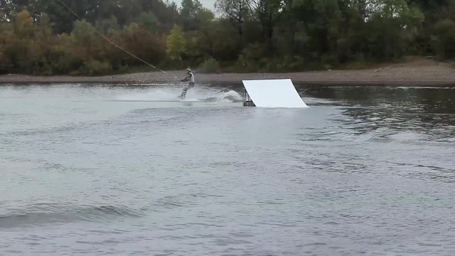 man on a wakeboard doing a back flip from a springboard. Beautiful and dangerous stunt. wakepark