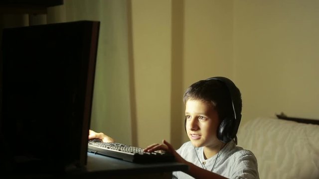 Teen boy plays games on the computer at night. Online Games