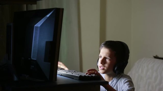 Teen boy plays games on the computer at night. Online Games