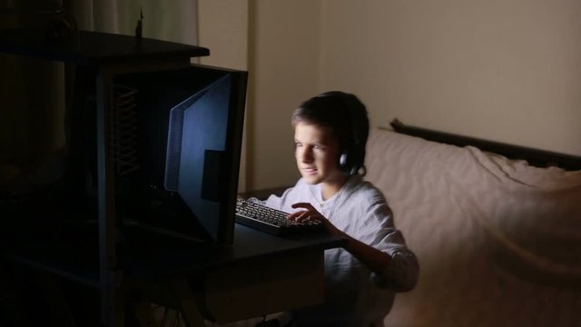 Teen boy plays games on the computer at night. Online Games