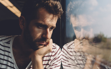 Sad young man looking through the window