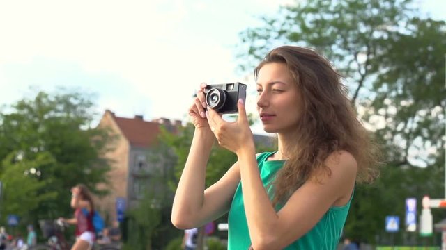 Girl doing photos on old camera in town, steadycam shot, slow motion shot at 240fps
