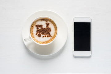 Fototapeta na wymiar Cup of coffee with train made of cinnamon and smartphone. Traveling concept/ online booking/ tickets