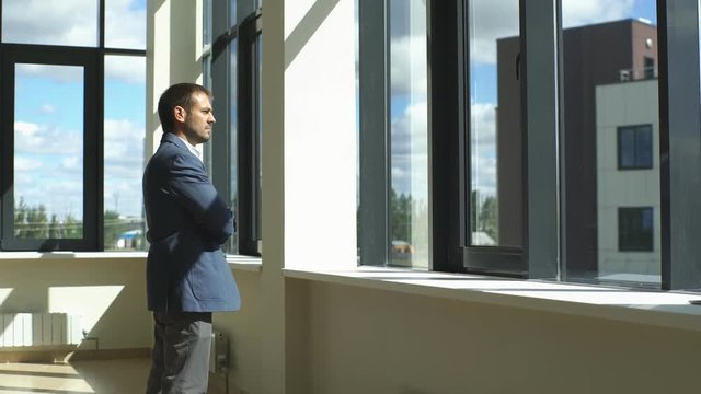 a successful businessman looks out the window and ponders the business plan