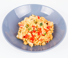 Risotto with chicken, tomatoes, bell pepper, onion, parsley and garlic on a blue plate on a wooden background