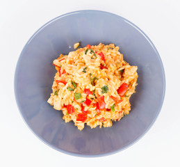 Risotto with chicken, tomatoes, bell pepper, onion, parsley and garlic on a blue plate on a wooden background