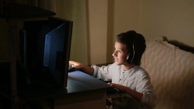 Teen boy plays games on the computer at night. Online Games