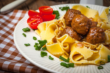 Tagliatelle, meatballs in dark sauce and tomato.