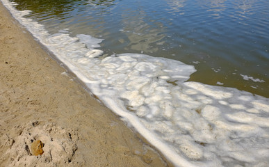 Schmutziges, schäumendes Wasser an einem Badesee
