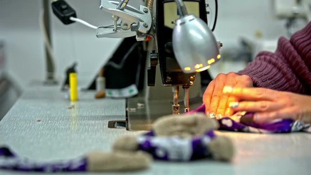 Person sewing plush toy on machine side shot