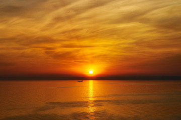 Bright sunset. Tranquil Sea. Fishing boat in the rays of the setting sun
