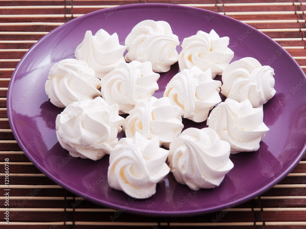 Poster meringues in a purple plate shot from above.