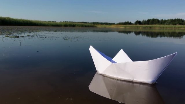 Boat made of paper floating on the river, close-up