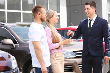 Fototapeta na wymiar Young couple buying car at dealership center