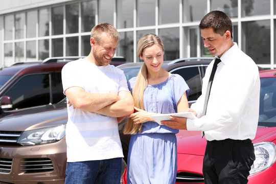 Young couple buying car at dealership center