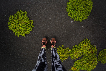 Girl legs on the black sand beach background