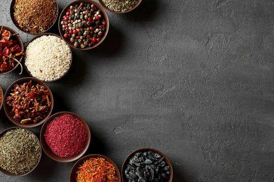 Different spices in bowls on grey textured background