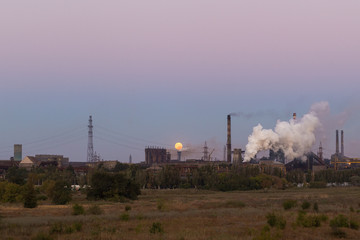 Fototapeta na wymiar Picture of metallurgical plant and its Smoking chimneys in the background of clear sky