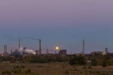 Fototapeta na wymiar Picture of metallurgical plant and its Smoking chimneys in the background of clear sky