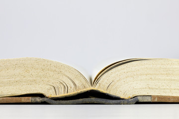 Open old book with yellow pages, over a grey background.