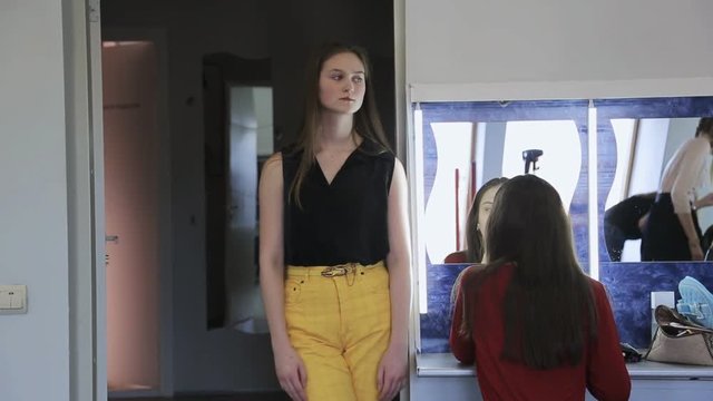 Beautiful girl in yellow trousers stands in dressing room.