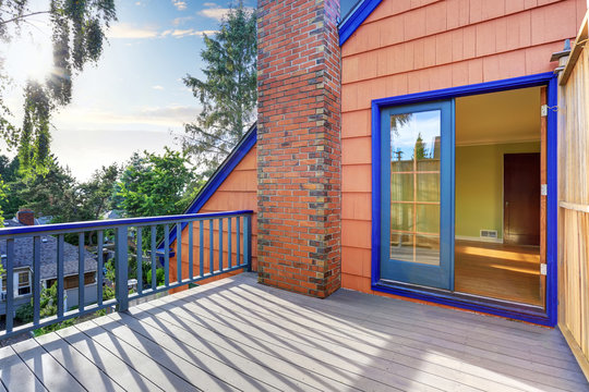 Wooden floor balcony of blue trim house in coral tones
