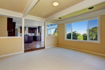 Open floor plan. Empty room with tile floor. View to kitchen room.