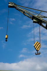 Fototapeta premium Black and yellow cranes hooks hanging on steel ropes