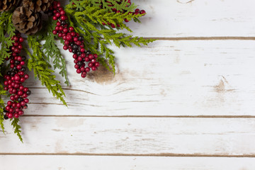 Christmas Garland with Pine Cones and Berries on a wood plank bo