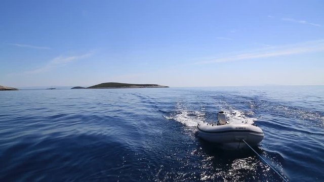 Scene of rubber dinghy in adriatic sea pulled by a boat.