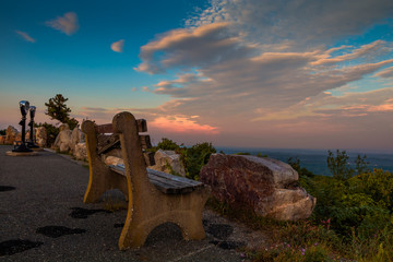 A lone bench and viewing binoculars look over the mountain at sunset 