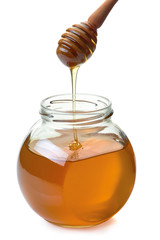 Jar with dripper an flowing honey on white
